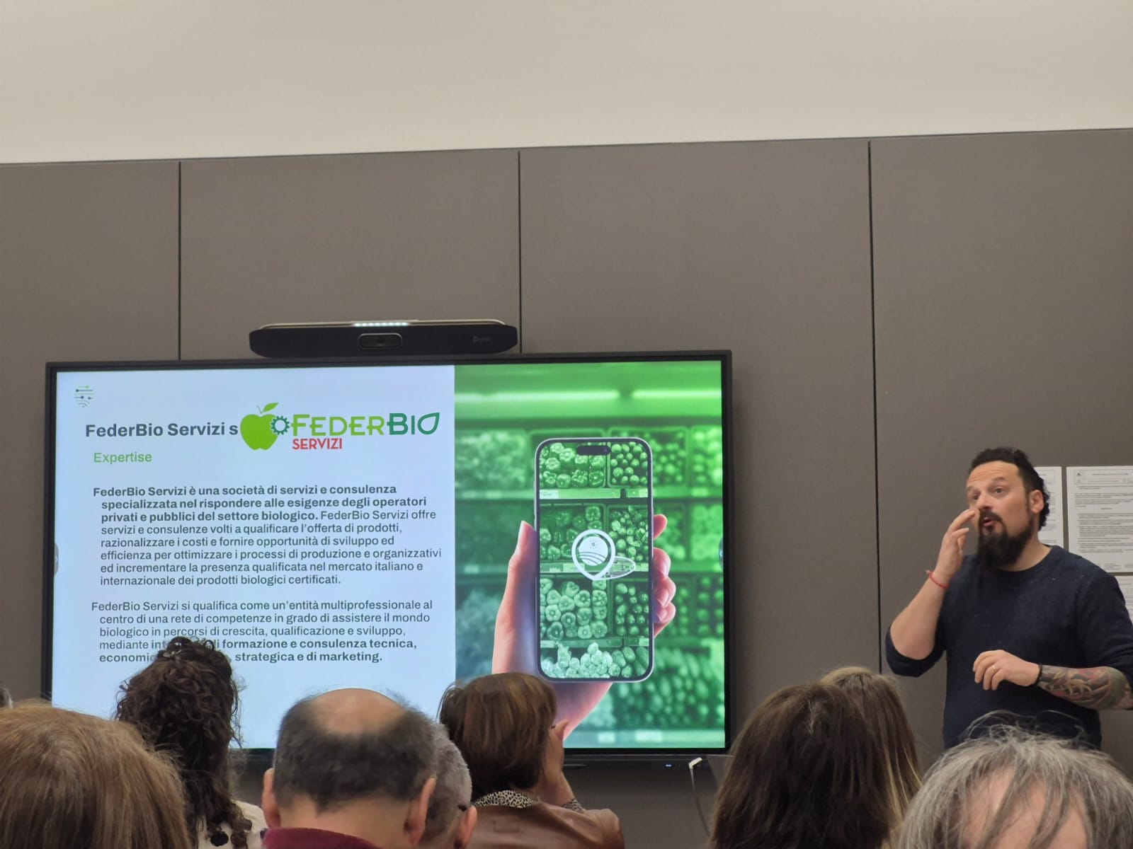 Simone Taddei of FederBio Servizi delivering his presentation. Several people in attendance can be seen from the back.