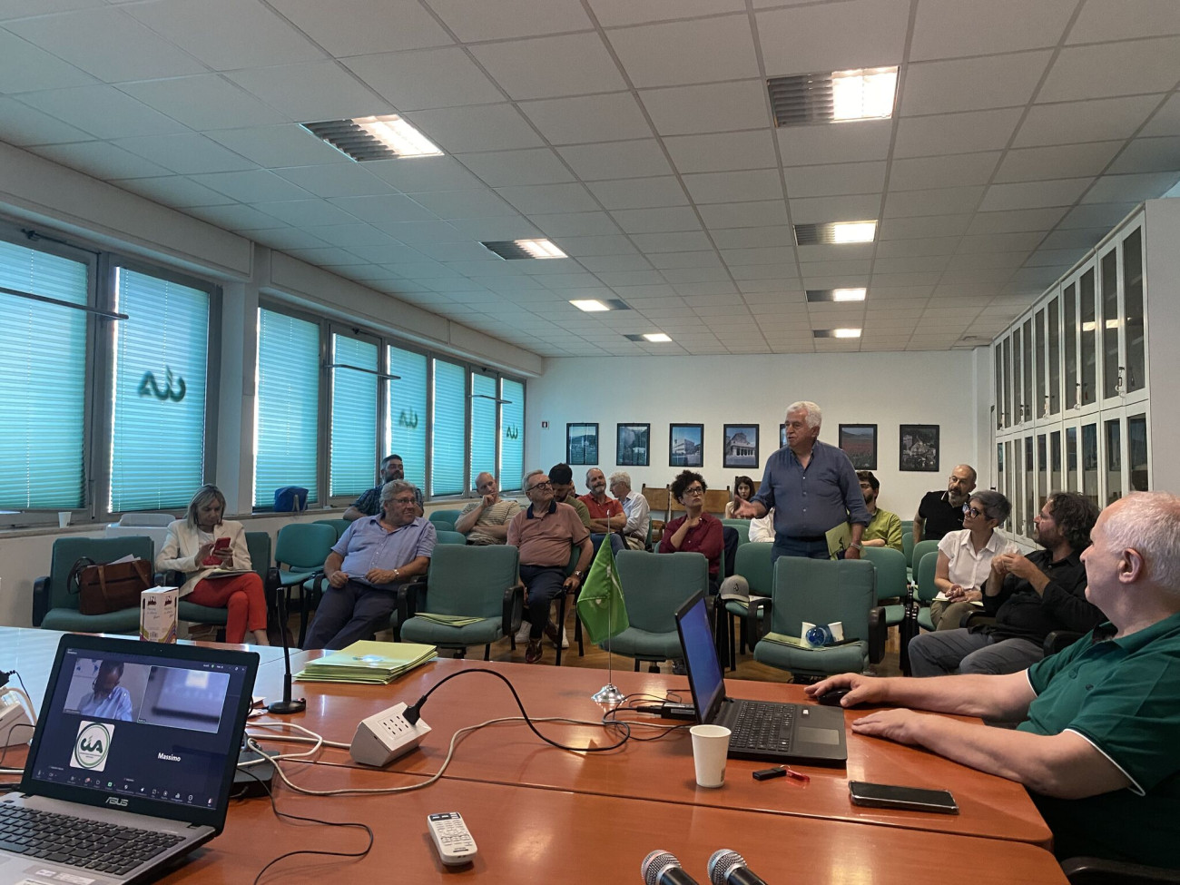 Audience members at the workshop. Several people are seated, one man is standing up and speaking.